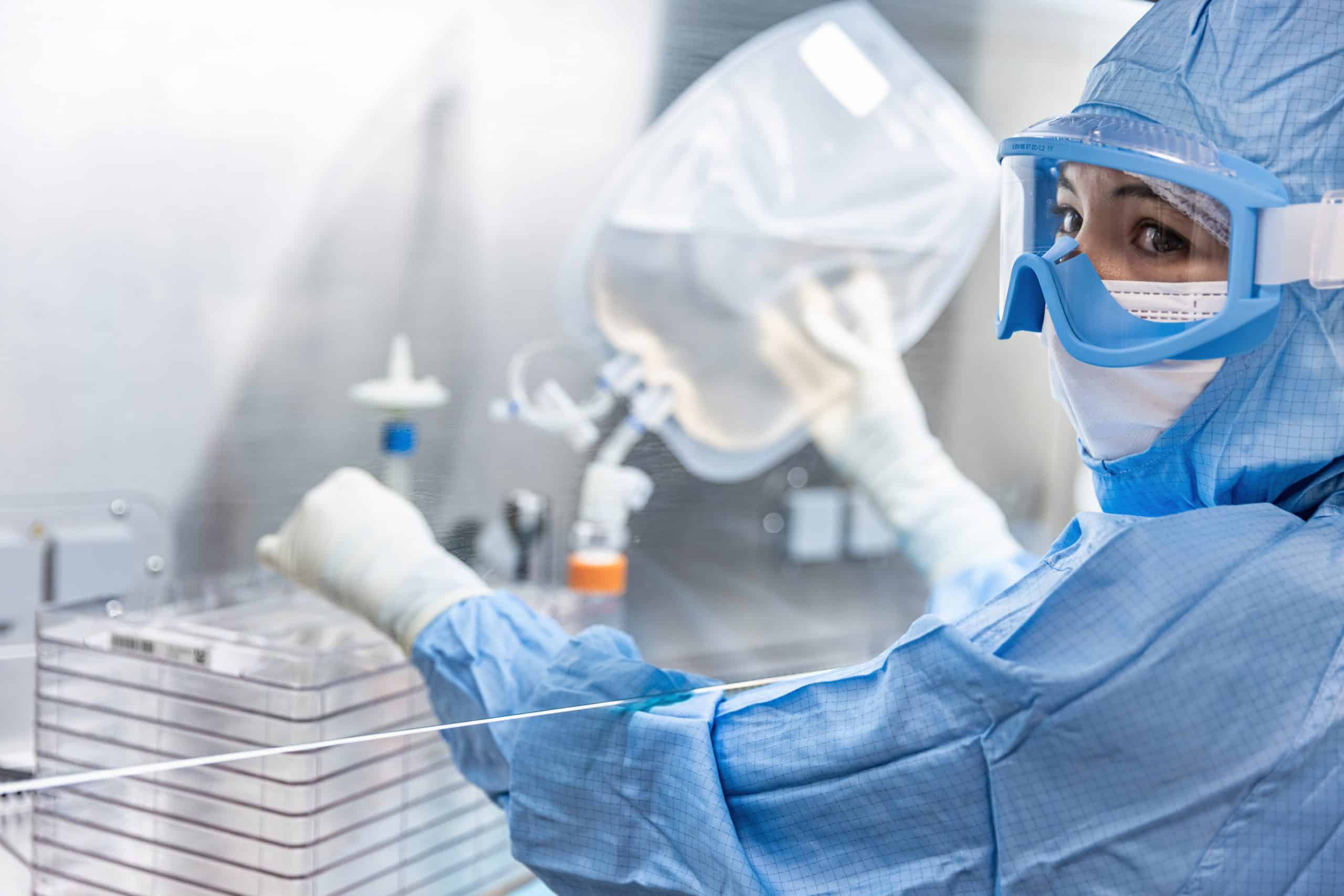 GMP operator in full PPE, seeding CellStack 10 with cells from the bag, containing the complete culture medium. - Cell-Easy